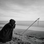 person near seashore grayscale photo