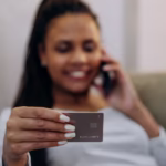 a woman holding a credit card while on the phone