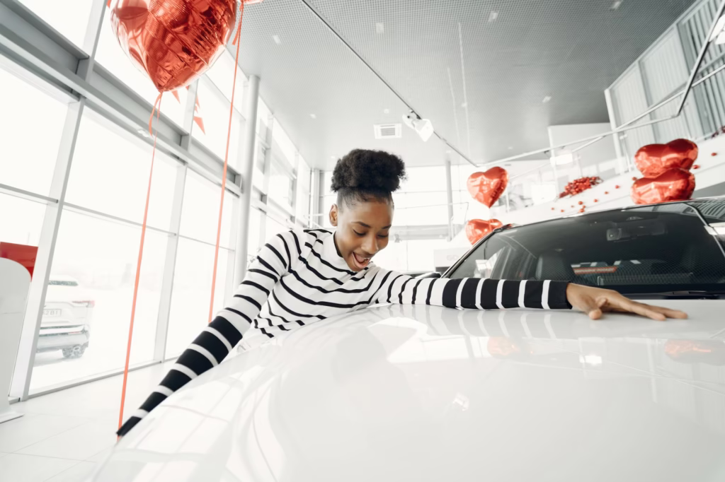 young woman touching a new car at car dealership