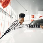 young woman touching a new car at car dealership