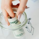 close up shot of a person saving money in the glass jar